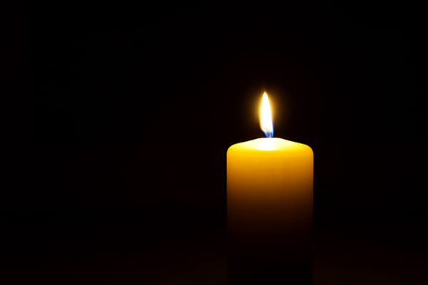 One yellow candle flame  burning in darkness on black background with copy space for text.