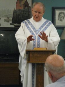 A priest standing at a pulpit in a white and blue vestibule